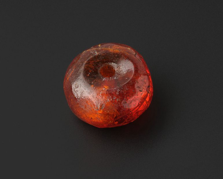 A small amber bead with a hole through the centre.