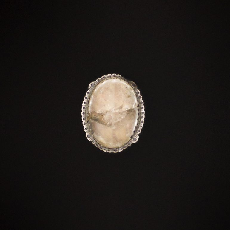 A small oval transparent charmstone set in a silver mount.