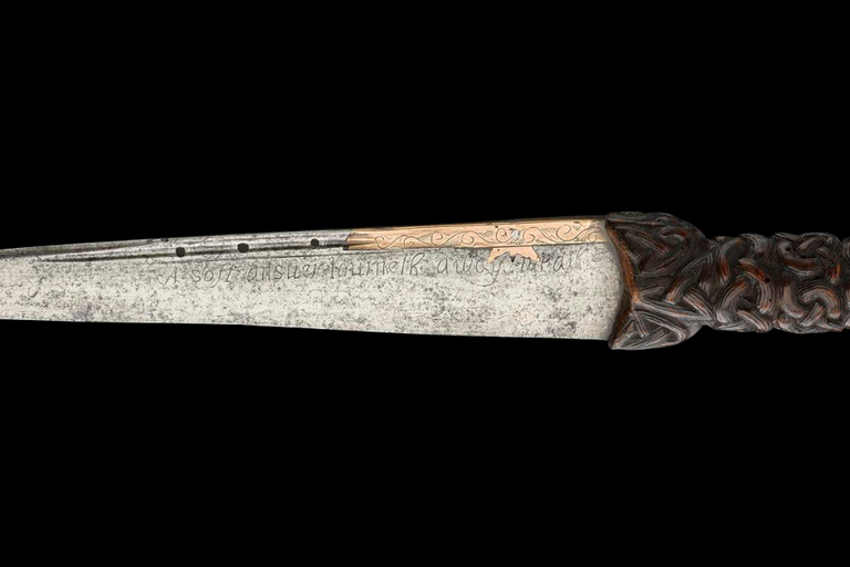 A traditional Highland dirk dagger with a metal blade and carved wooden hilt.