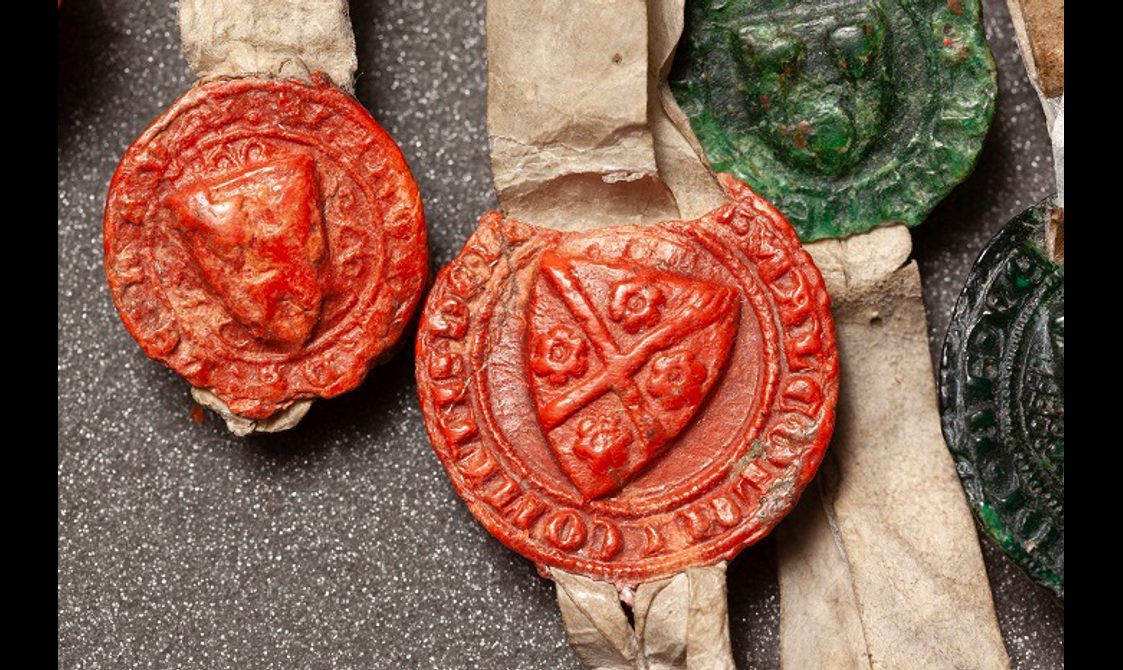 Round red and green seals with heraldic shields surrounded by lettering.