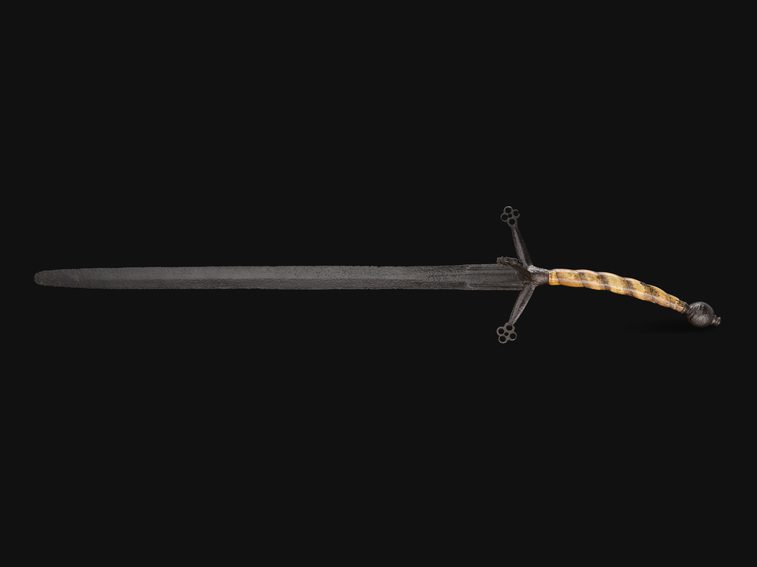 A two-handed black claymore sword with four down-pointing quillons and a tan curved tusk grip