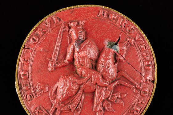 Closeup of a red wax seal. The seal has a picture of Robert the Bruce carrying a sword and riding a horse. Lettering around seal edge.
