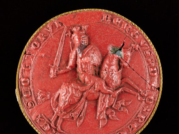 Closeup of a red wax seal. The seal has a picture of Robert the Bruce carrying a sword and riding a horse. Lettering around seal edge.