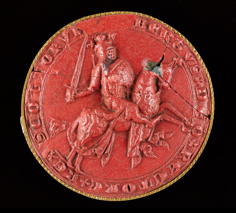 Closeup of a red wax seal. The seal has a picture of Robert the Bruce carrying a sword and riding a horse. Lettering around seal edge.