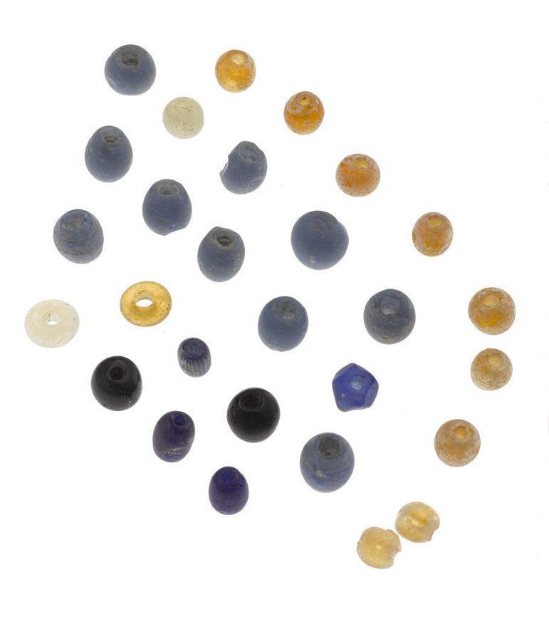 A set of multicoloured glass beads arranged on a white background. The collection are if blue, grey, black yellow and white and arranged in a diagonal grid.