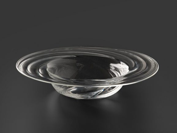 A wide shallow glass bowl against a black background. The bowl has a wide flat rim and a small bowl. The rim has a twisted undulating ripple pattern.