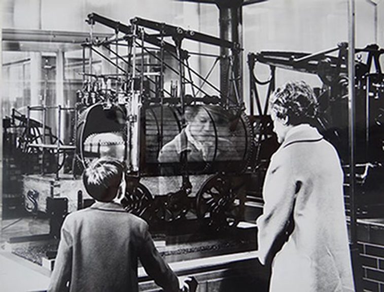 A black and white photo of a child and adult looking at a museum exhibit