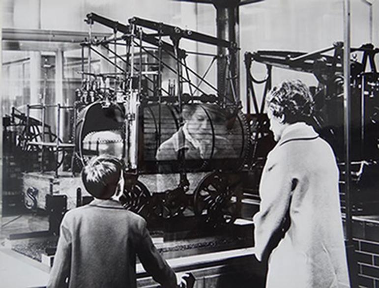 A black and white photo of a child and adult looking at a museum exhibit