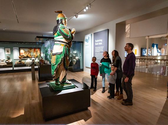 A family looking up at a statue in the Exploring East Asia gallery.