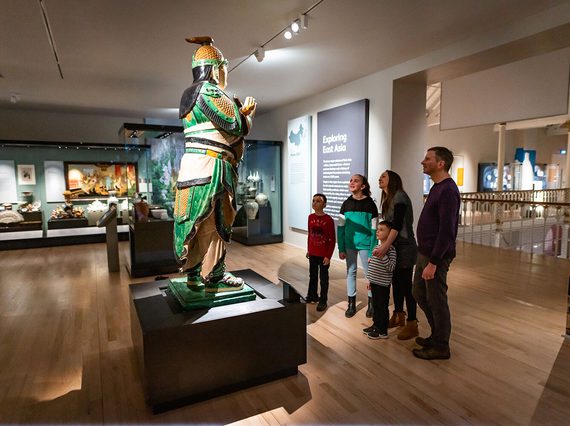 A family looking up at a statue in the Exploring East Asia gallery.