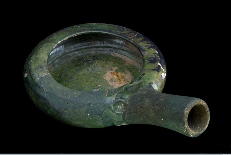 A green bedpan in a round shape with a spout protruding.