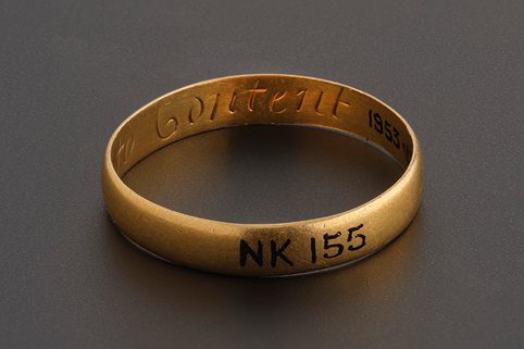 A gold posy ring with plain band. The word 'content' of the phrase 'No Richese to content' can be seen inside the band.