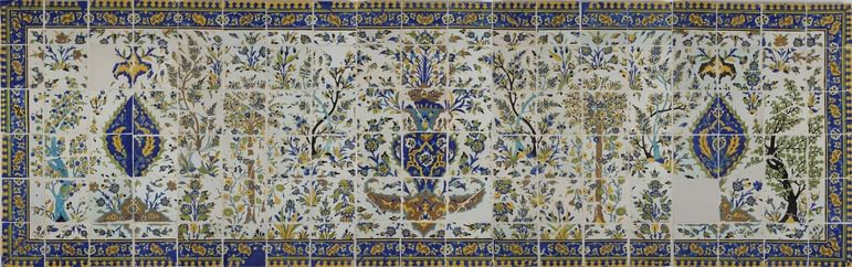 A long, rectangular panel made of hundreds of intricately decorated, painted tiles. This image gives the overall impression of the illustration, which from a distance is of a garden scene with trees all around, and a fountain as the centrepiece. The colours painted are yellow, blue, green and brown.