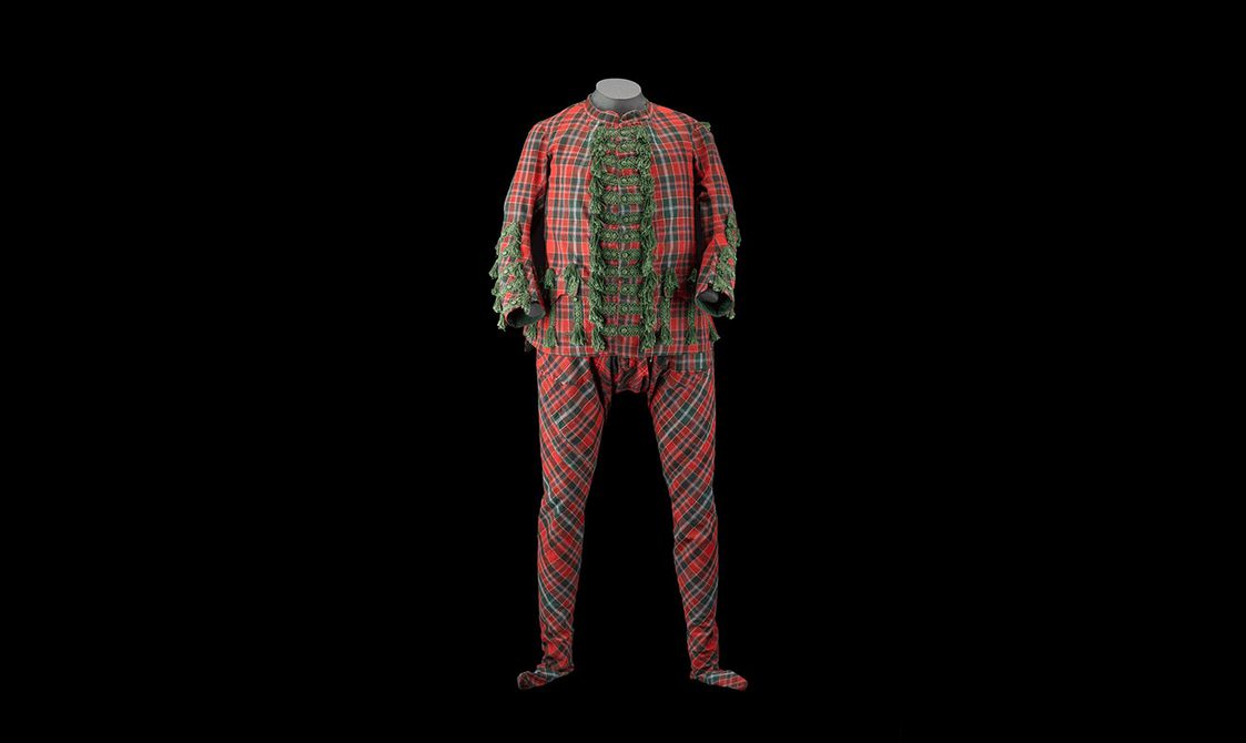 Front view of a red and green tartan full body suit. There are frilly green buttons down the middle and along the sleeves.