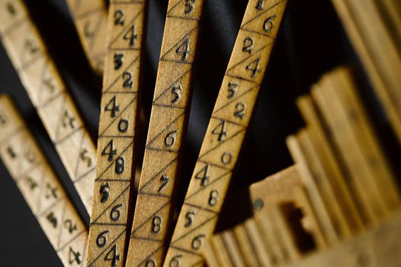 A colour photograph of a close-up of some wooden sticks with number pairs separated by diagonal lines.