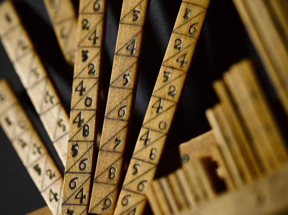 A colour photograph of a close-up of some wooden sticks with number pairs separated by diagonal lines.