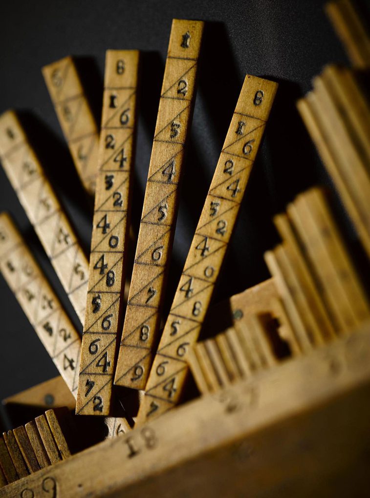 A colour photograph of a close-up of some wooden sticks with number pairs separated by diagonal lines.