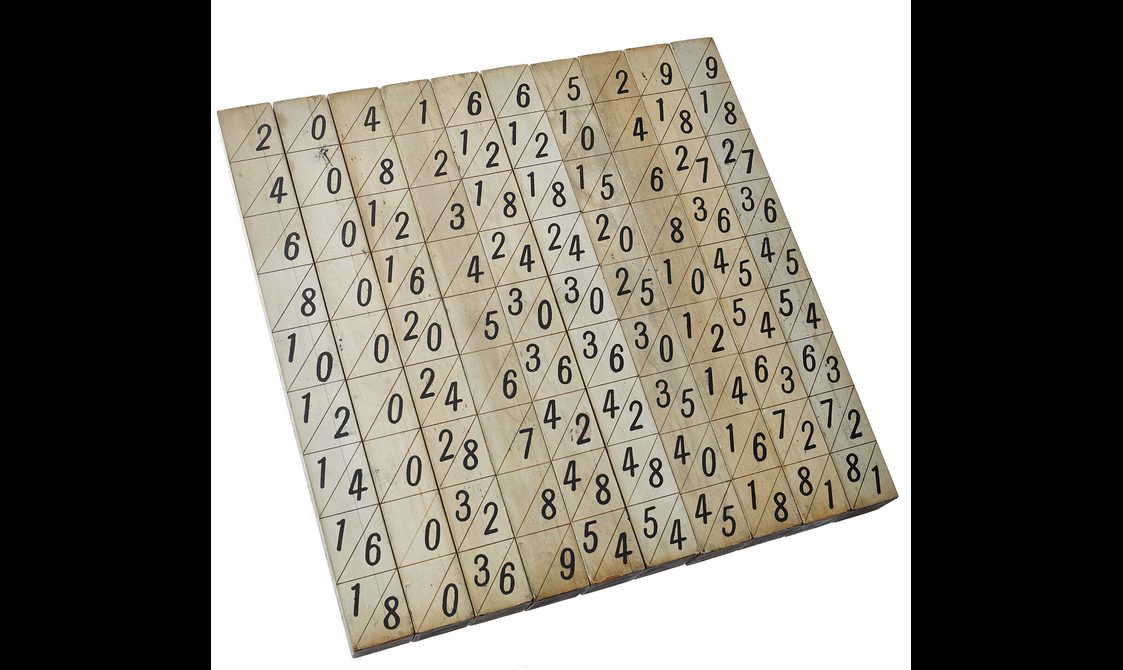 A colour photograph of a set of wooden strips placed together to form a square. Each strip has a set of numbers.