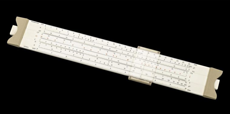 A colour photograph of a long white instrument similar to a ruler against a black background. The devoice has a slider attached and many lines of numbers horizontally across.