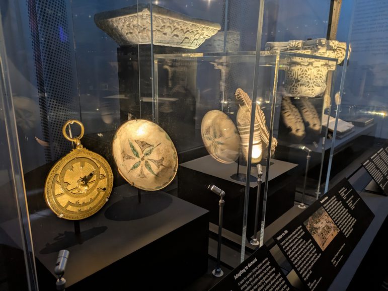 The museum's bronze astrolabe with an assortment of other objects on display behind glass at the British Museum’s Silk Roads exhibition.