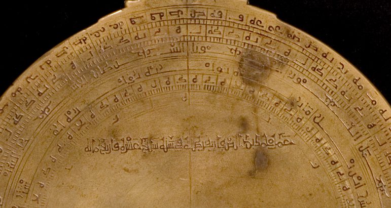 Zoomed in details of the edge of the astrolabe with foreign language inscriptions.