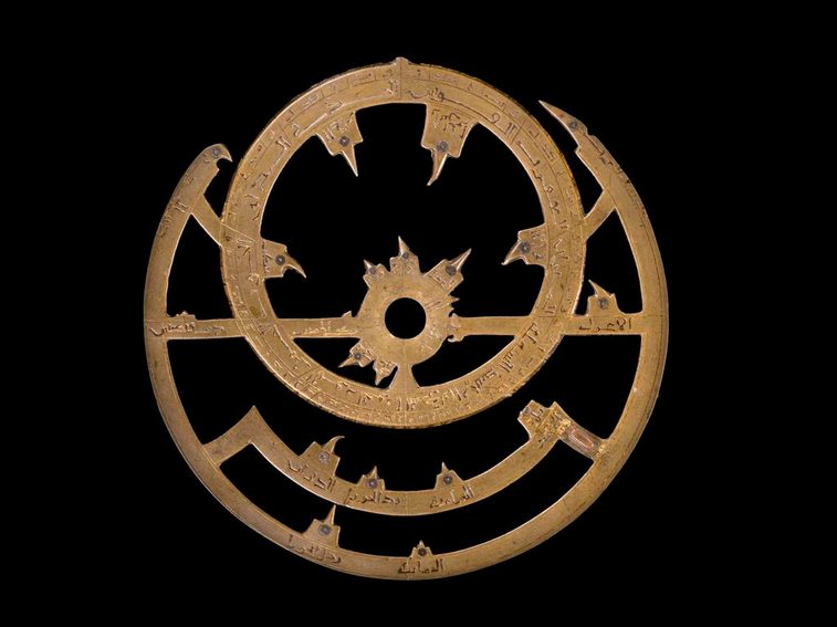 An ornate front component of the astrolabe in bronze metal, showing pointers to stellar positions.