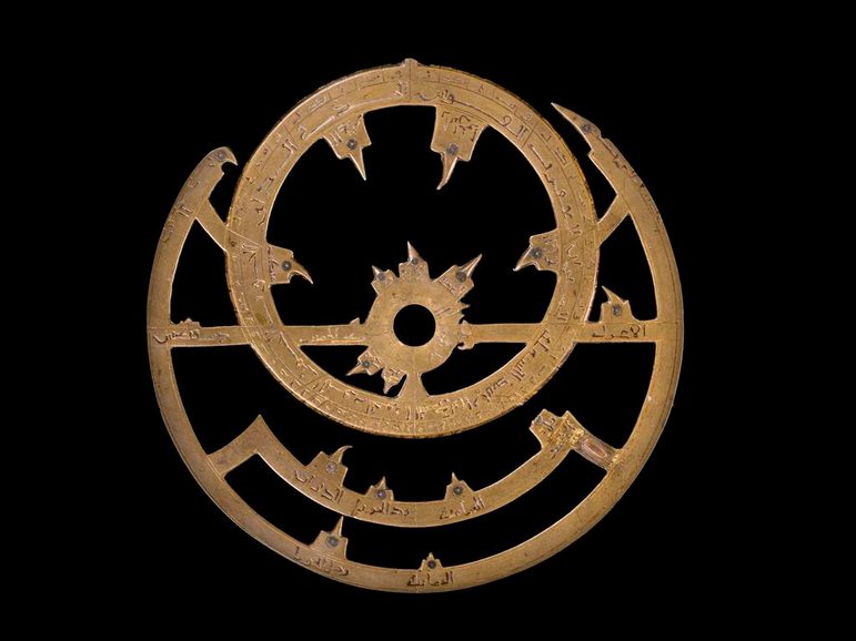 An ornate front component of the astrolabe in bronze metal, showing pointers to stellar positions.