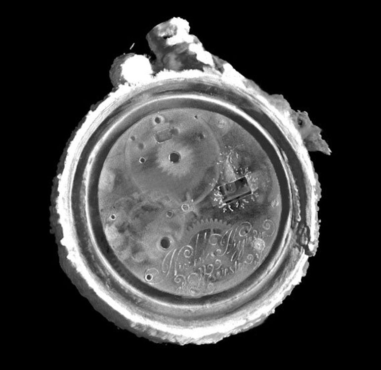 A black and white scan showing the insides of a circular watch from head on and from the back. There is an engraving on the bottom middle. There is also a ghostly image of the cogs and wheels that are in the middle of the watch. The outside of the watch shows a bumpy outer crust