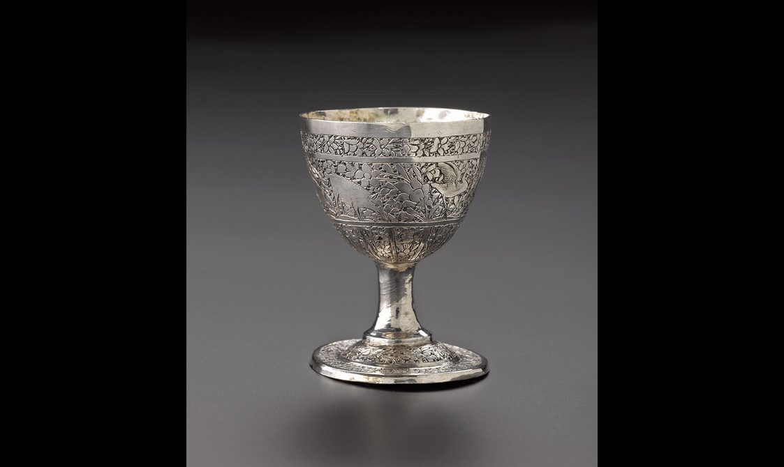A silver egg cup with floral patterns decorating the cup's surface.