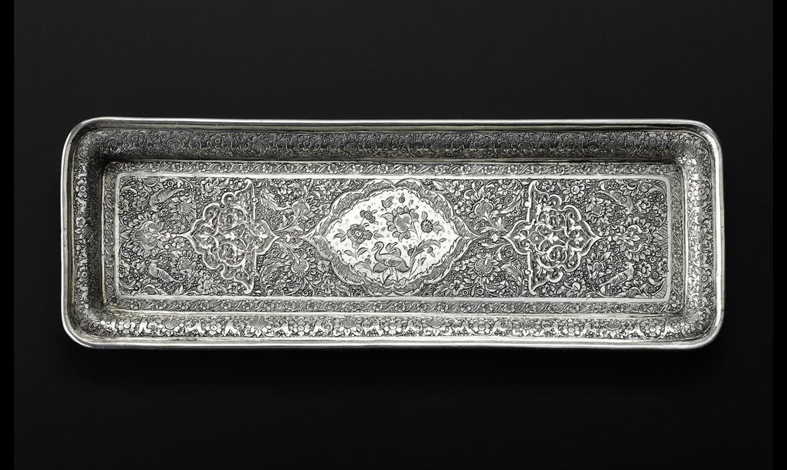 A long rectangular silver tray with a highly decorated surface.