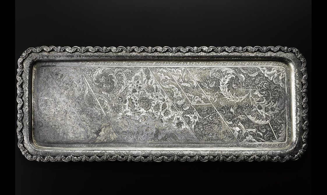 A long rectangular silver tray with floral patterns engraved all over its surface.