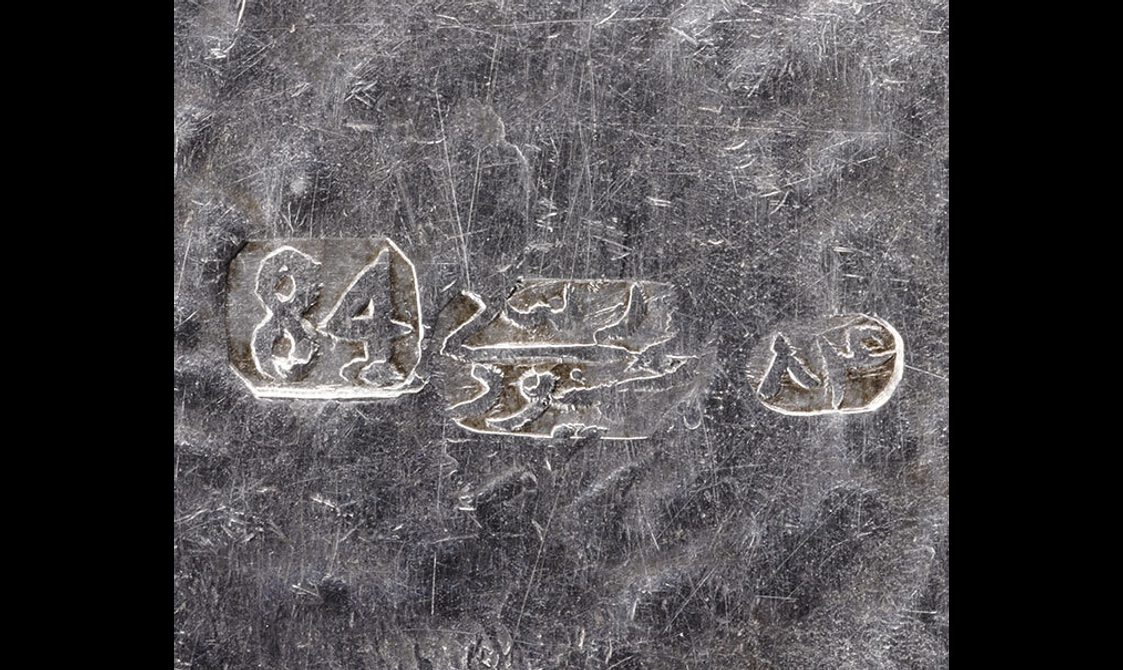 Detail of a silver object with three stamped marks indicating the makers.