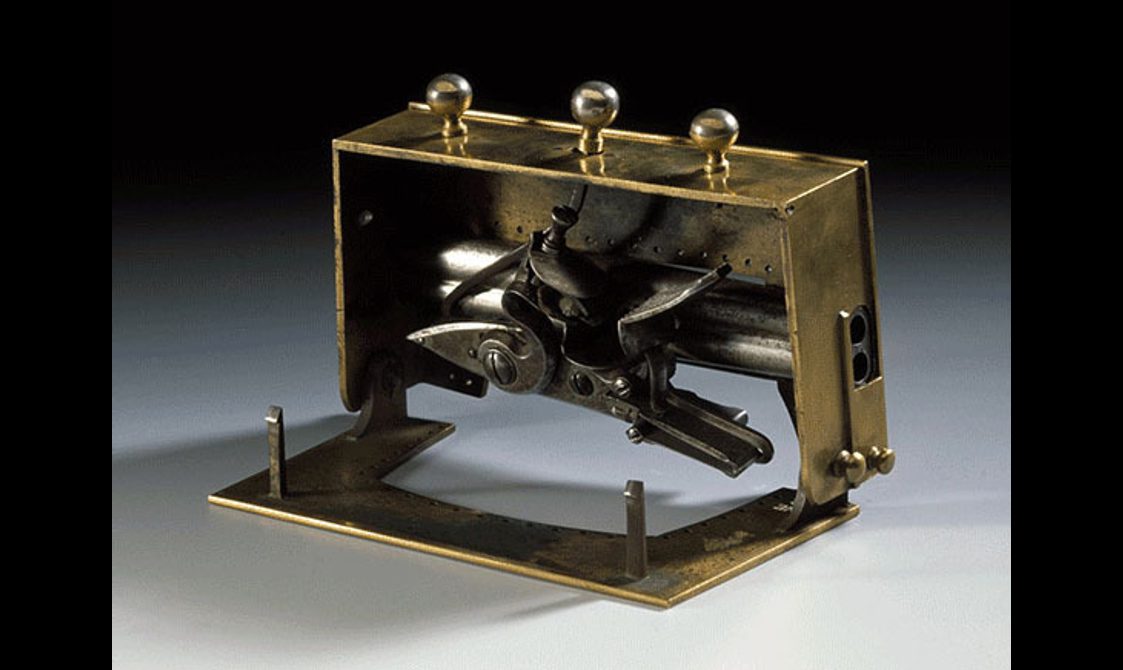 Side view of an open brass sporran clasp with hidden pistols inside.
