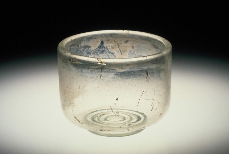 Small, translucent glass cup wider than it is tall against a dark background.