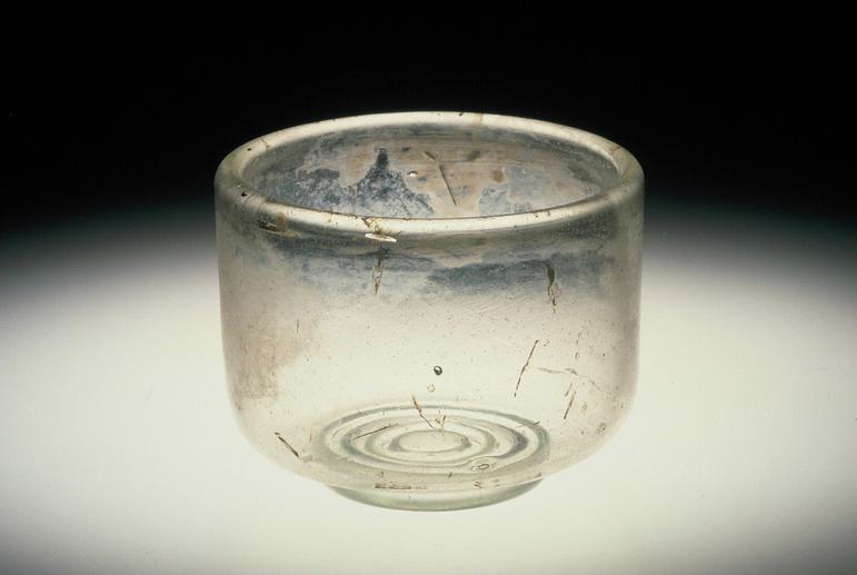 Small, translucent glass cup wider than it is tall against a dark background.