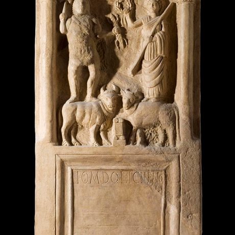 Very smooth and finely carved altar shaped a bit like how a child would draw a house. Two humanoid figures and two cattle gather around a central altar.