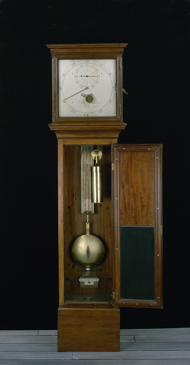 A grand longcase standing clock with a white face and large brass pendulum.