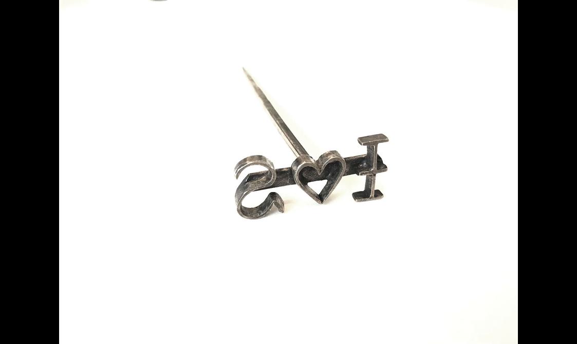 A T shaped pin like metal branding tool with reverse text I heart symbol S