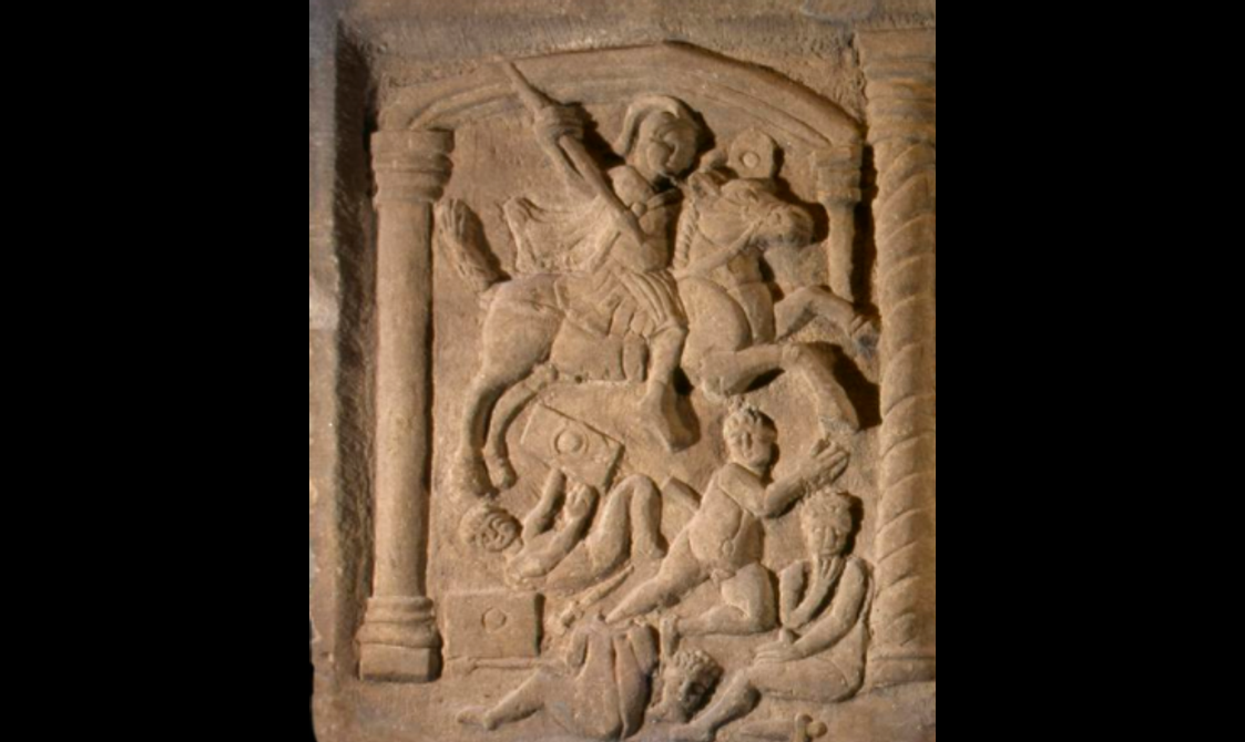 Close-up of a fine carving showing a mounted soldier trampling over nude, cherub-like people.