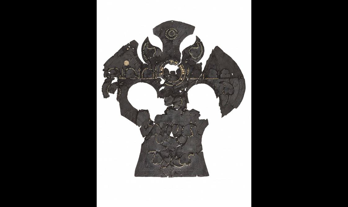 Badly degraded but still obviously prestigious blackened leather horse helmet, laid out flat with several patches missing.