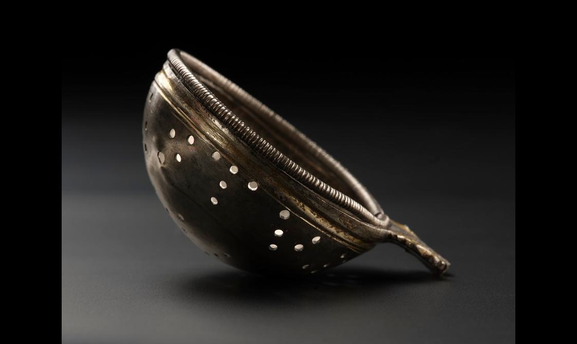 Small strainer tipped on its side, with two thin golden rims and a mahogany-like colour.