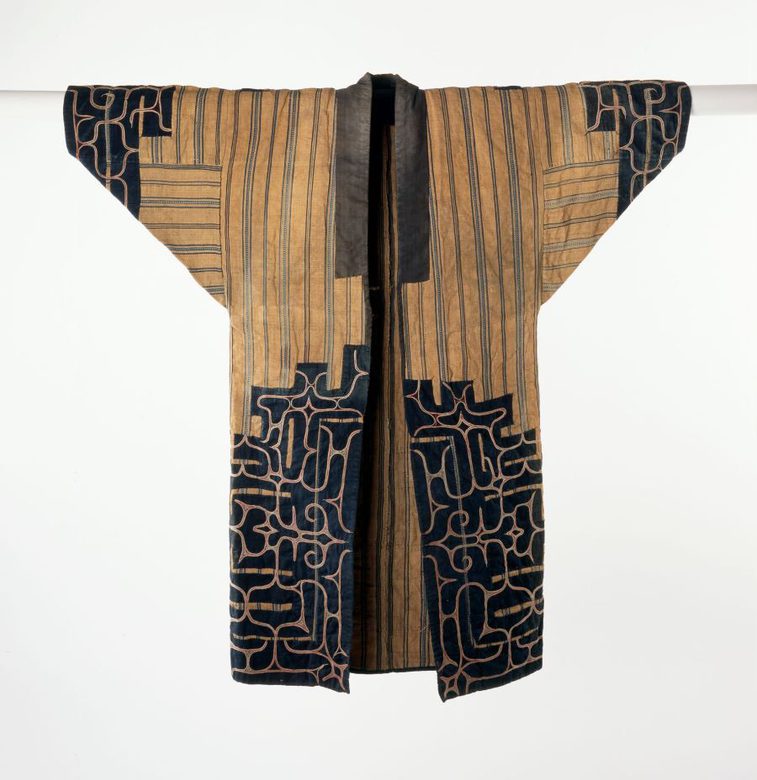 A light brown and navy long jacket with wide sleeves laid flat. The cuffs and bottom of the jacket are decorated in navy with an abstract pattern.