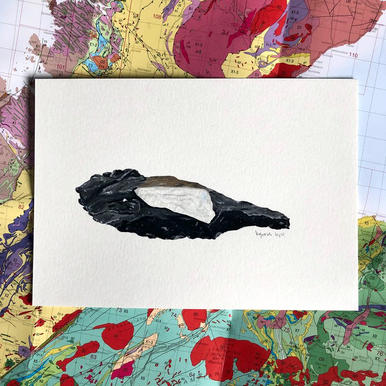 An illustration of dark grey and white mineral on a white piece of paper. The illustration is photographed against a geological map of Scotland.