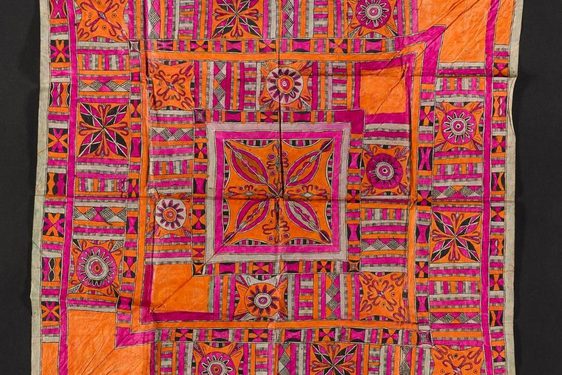 A square piece of pink and orange textile laid flat. It has intricate geometric patterns.