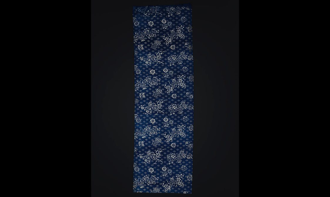 Repeating blue and white intricate organic design printed on a length of cotton