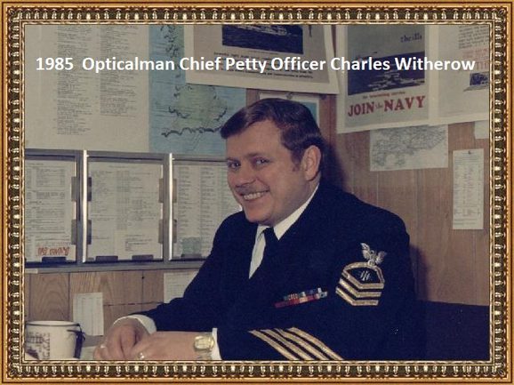 A seated man wearing US Naval uniform smiles at the camera.