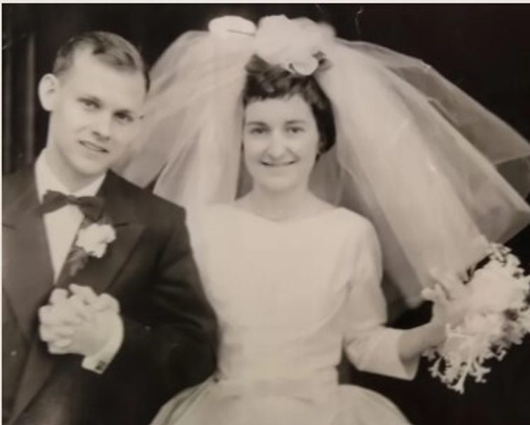 A sepia photography of a bride and bridegroom The bride is wearing a large veil and the groom has a flower pinned to his lapel