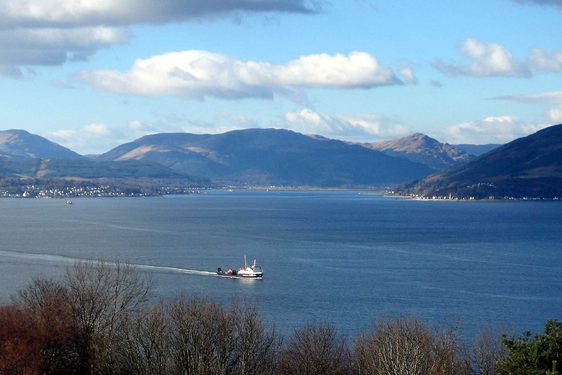 The Holy Loch near Dunoon. A large loch with mountains in the distance. A white ferry travels across the loch.