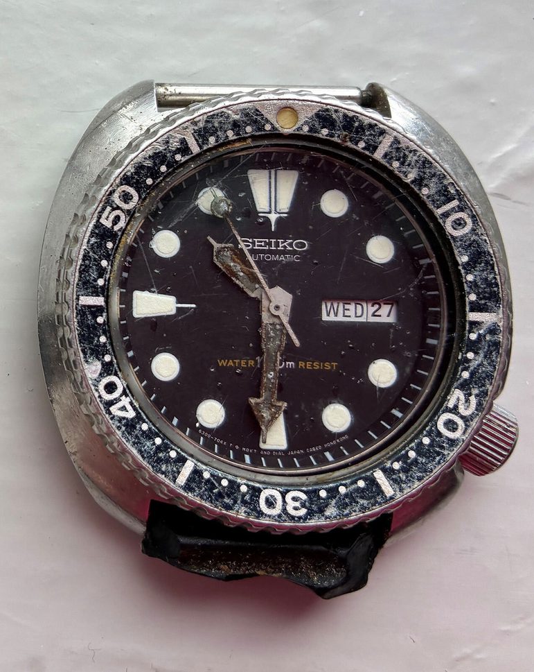 A Seiko-branded watch face showing significant signs of wear and tear