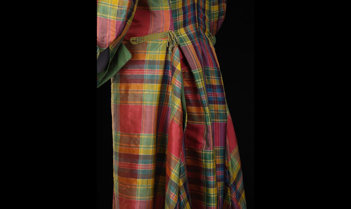 Detail of a red, green, and yellow silk tartan coat with gathers at the waist